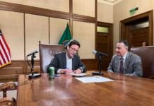 Gov. Bob Ferguson signs documents on Tuesday, Dec. 2, 2025 certifying the results of Washington’s 2025 general election.