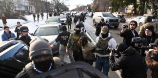 An observer is detained by ICE agents after they arrested two people from a residence on Jan. 13, 2026 in Minneapolis