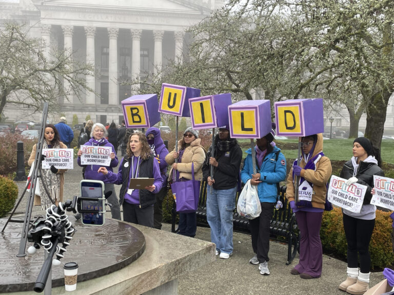 Tricia Schroeder of SEIU Local 925, center, speaks at a Jan. 19, 2026 rally of early learning and child care professionals who seek better wages and benefits and oppose proposed cuts to programs that could leave families with fewer child care options. (Photo by Jerry Cornfield/Washington State Standard)