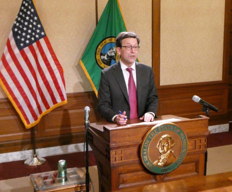In a departure from the norm, no one stood beside Gov. Bob Ferguson on Wednesday when he signed House Bill 2367, the tax and fee revisions targeting coal power. House bill sponsors were still recovering from an all-nighter involving debate over a state income tax. (Photo by Tom Banse)