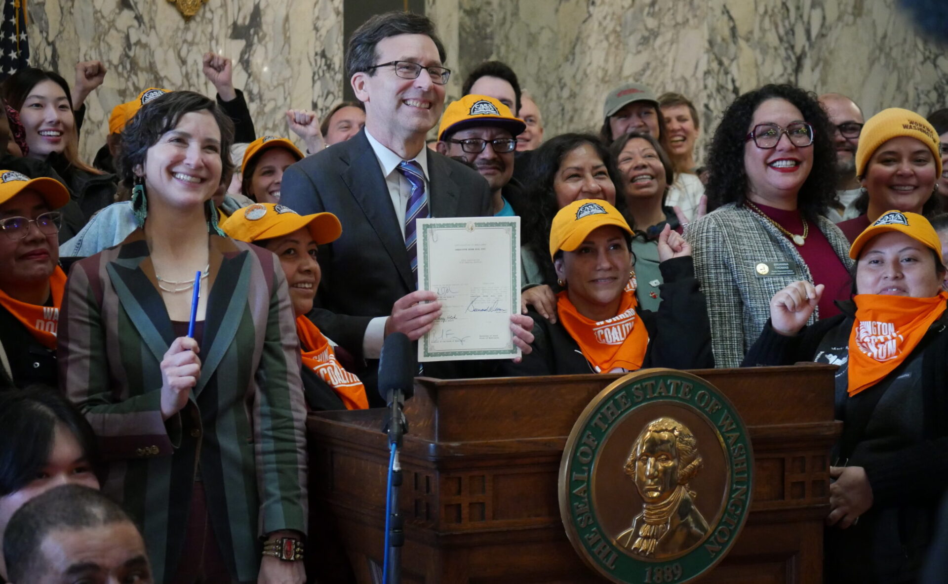 Governor Bob Ferguson appears with supporters of the bill after signing the legislation into law on March 9, 2026. House Bill 2355 establishes labor rights for nannies, gardeners and other domestic workers