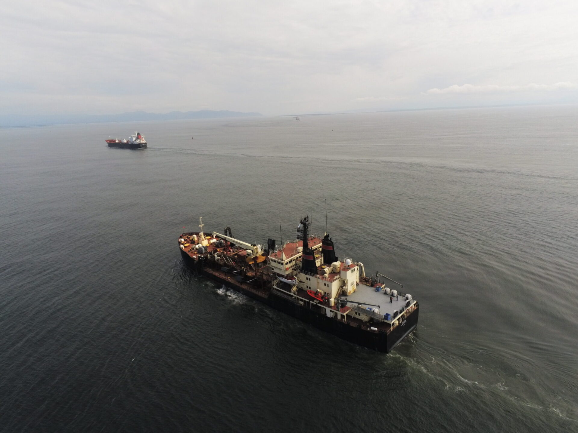 Two dredging vessels, the government-owned Essayons and the Bayport, a contract vessel, at the mount of the Columbia River.