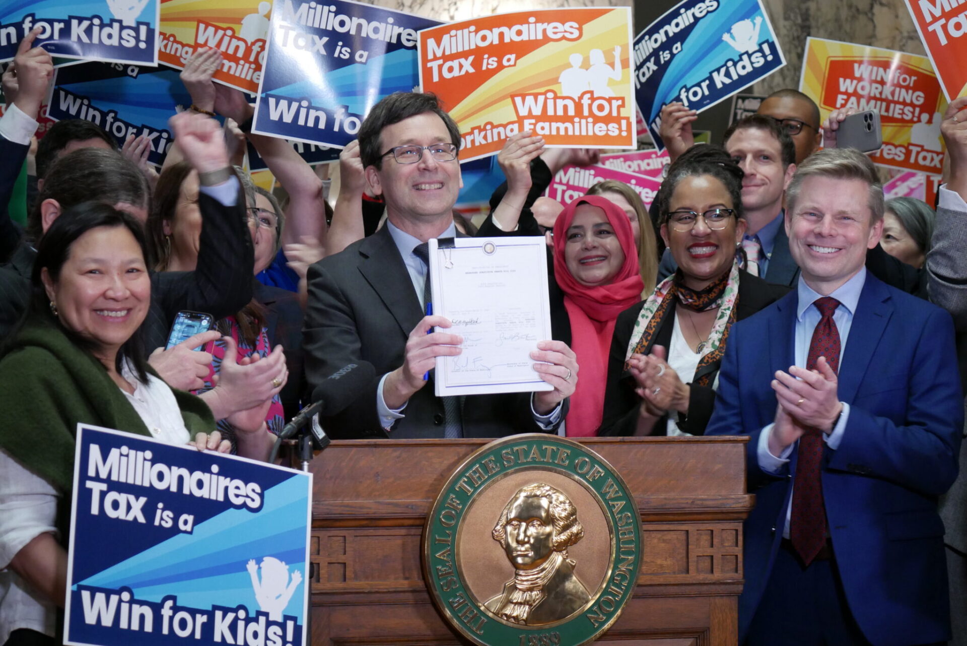 Supporters of Washington’s new income tax on millionaires celebrate after Gov. Bob Ferguson signs the bill into law on Monday March 30, 2026