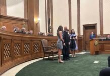 Washington state Supreme Court Justice Theo Angelis dons his robe alongside wife Kim and children Katherine and John as he is sworn in as a justice at the Temple of Justice on Monday, May 18, 2026, in Olympia