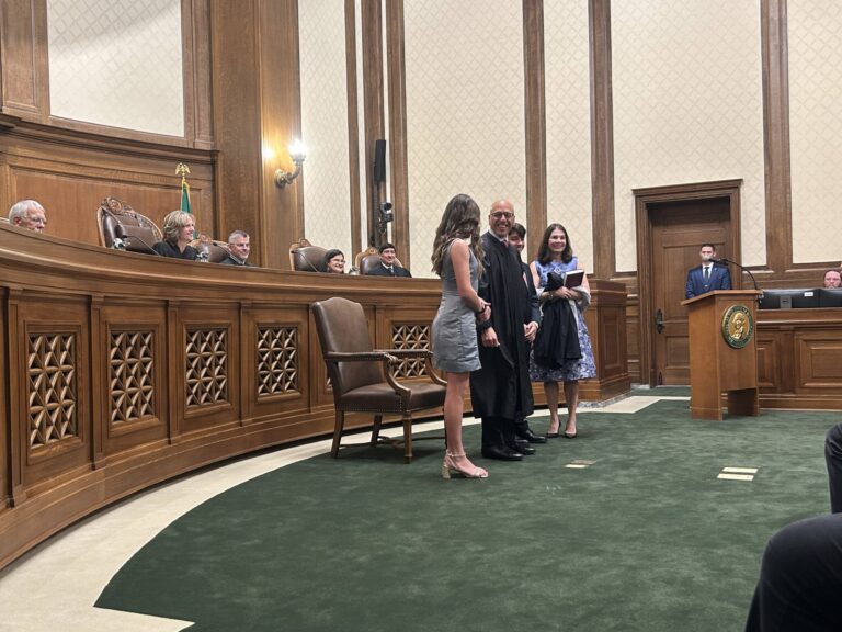 Washington state Supreme Court Justice Theo Angelis dons his robe alongside wife Kim and children Katherine and John as he is sworn in as a justice at the Temple of Justice on Monday, May 18, 2026, in Olympia