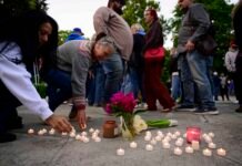 Community members place electric candles near a vase of flowers during a vigil at R.A. Long Park following a fatal chemical storage tank failure on May 26, 2026 in Longview, Washington.