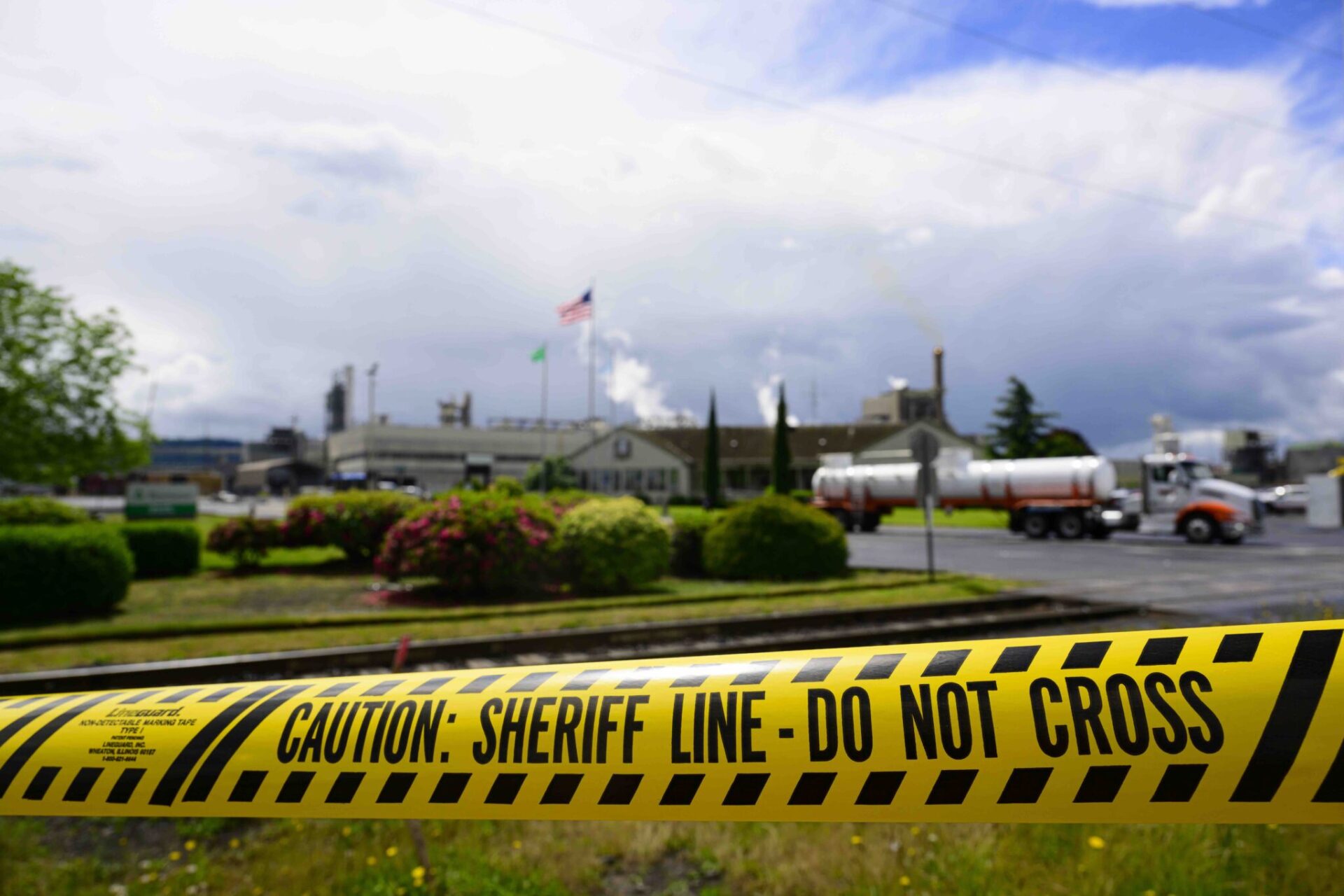 Emergency tape reading “Caution: Sheriff Line – Do Not Cross” is seen in front of the Nippon Dynawave Packaging facility following a fatal chemical storage tank implosion on May 26, 2026 in Longview, Washington.