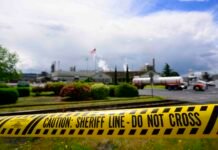 Emergency tape reading “Caution: Sheriff Line – Do Not Cross” is seen in front of the Nippon Dynawave Packaging facility following a fatal chemical storage tank implosion on May 26, 2026 in Longview, Washington.