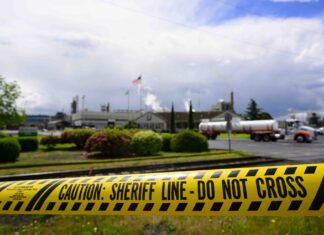WA agencies lacked role inspecting failed chemical tank in Longview mill disaster Emergency tape reading “Caution: Sheriff Line – Do Not Cross” is seen in front of the Nippon Dynawave Packaging facility following a fatal chemical storage tank implosion on May 26, 2026 in Longview, Washington.