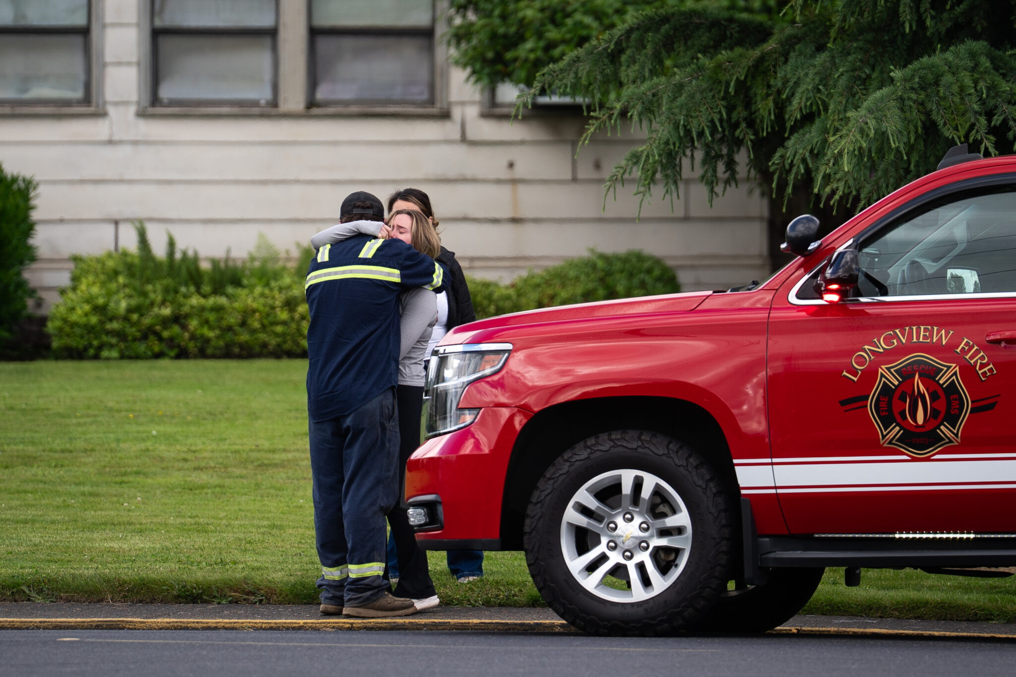 People share an emotional embrace outside of Nippon Dynawave Packing Company after a chemical tank burst early in the morning at the Longview, Wash., facility on May 26, 2026. (Photo by Eli Imadali/Oregon Public Broadcasting)