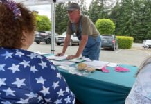 Doug Hicks signs a initiative petition on June 3, 2026 in Tumwater, Washington. The proposed ballot measure would repeal a statewide income tax on high earners enacted earlier this year