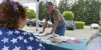 Doug Hicks signs a initiative petition on June 3, 2026 in Tumwater, Washington. The proposed ballot measure would repeal a statewide income tax on high earners enacted earlier this year