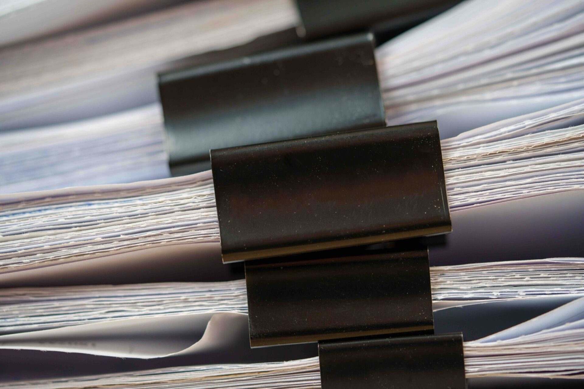 Piles of white papers Stacks of office working paper documents files with black clip on the desk in the office .