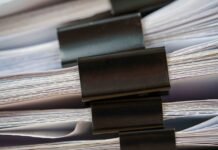 Piles of white papers Stacks of office working paper documents files with black clip on the desk in the office .