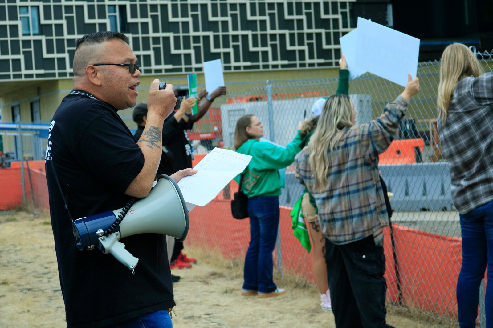 Mark Camacho, union member, uses a megaphone to lead chanting workers at a ceremony for a new psychiatric facility at the Western State Hospital campus. (Photo by Aspen Ford/Washington State Standard)
