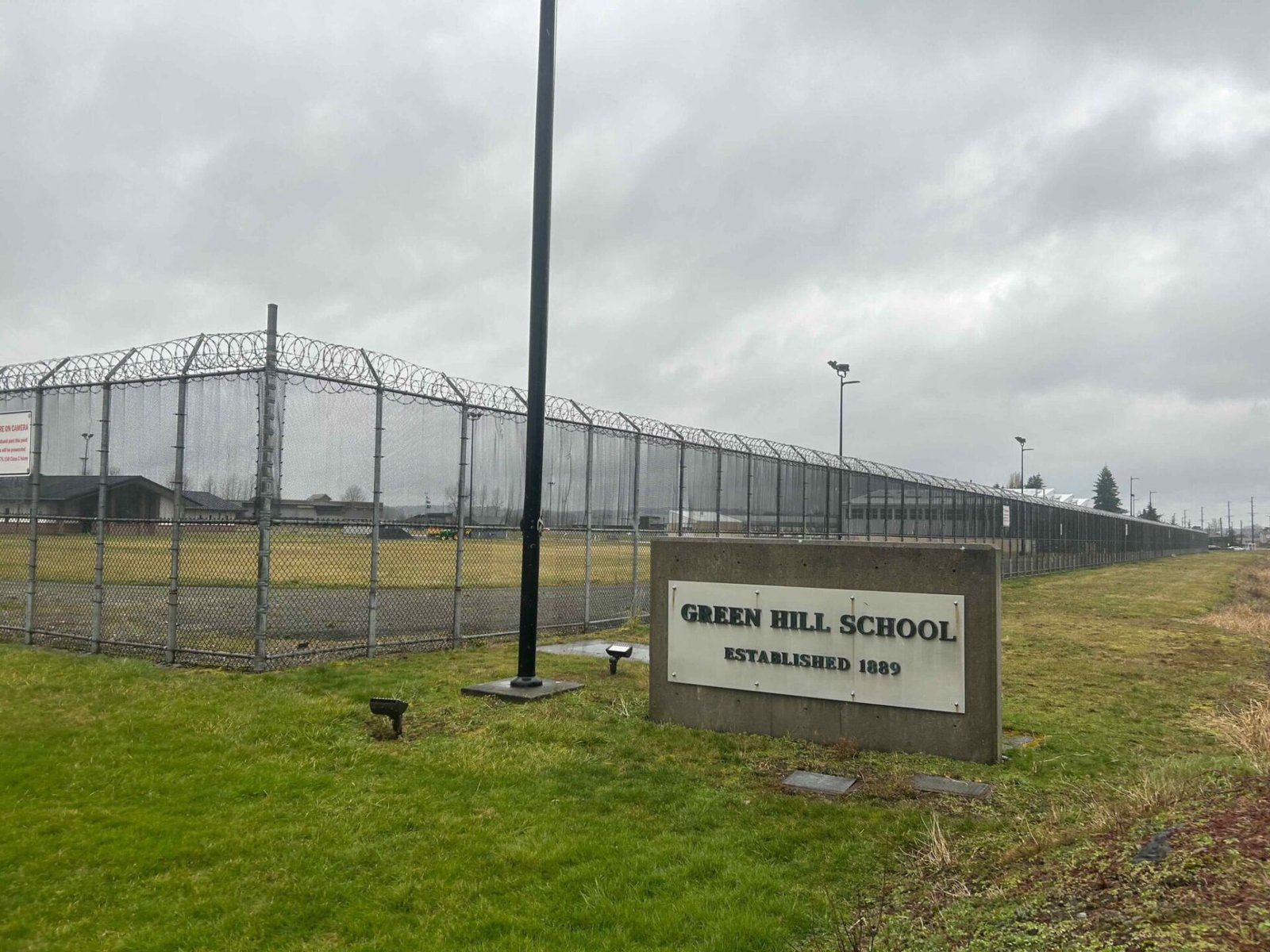 A sign and fence at the Green Hill School for juvenile offenders, in Chehalis, Washington. (Photo by Jake Goldstein-Street/Washington State Standard)