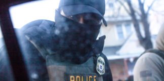 A masked U.S. Immigration and Customs Enforcement agent knocks on a car window in Minnesota on Jan. 12. (Photo by Nicole Neri/Minnesota Reformer)